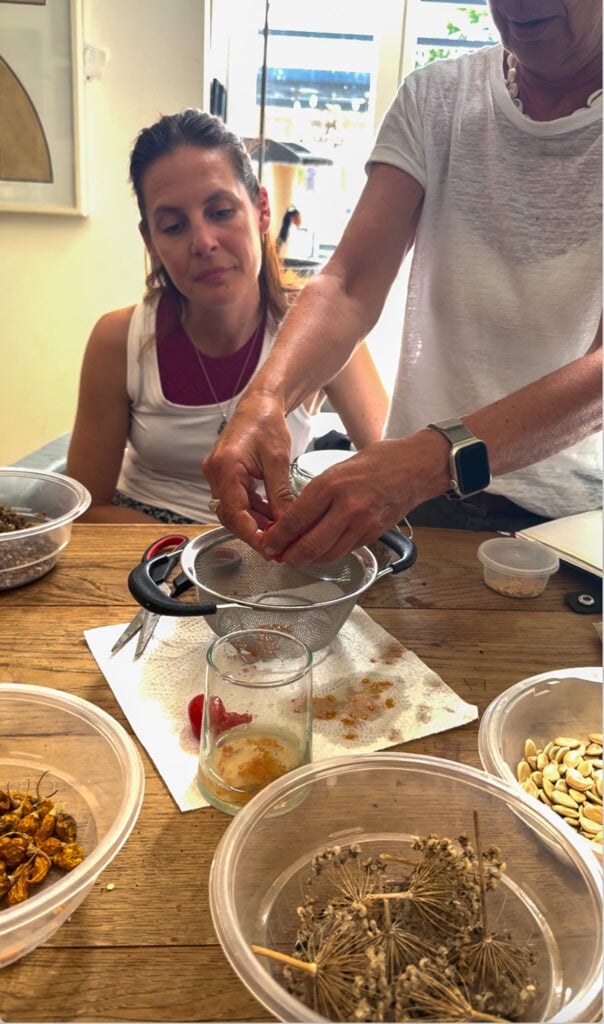 People cleaning seeds with sieve and containers.