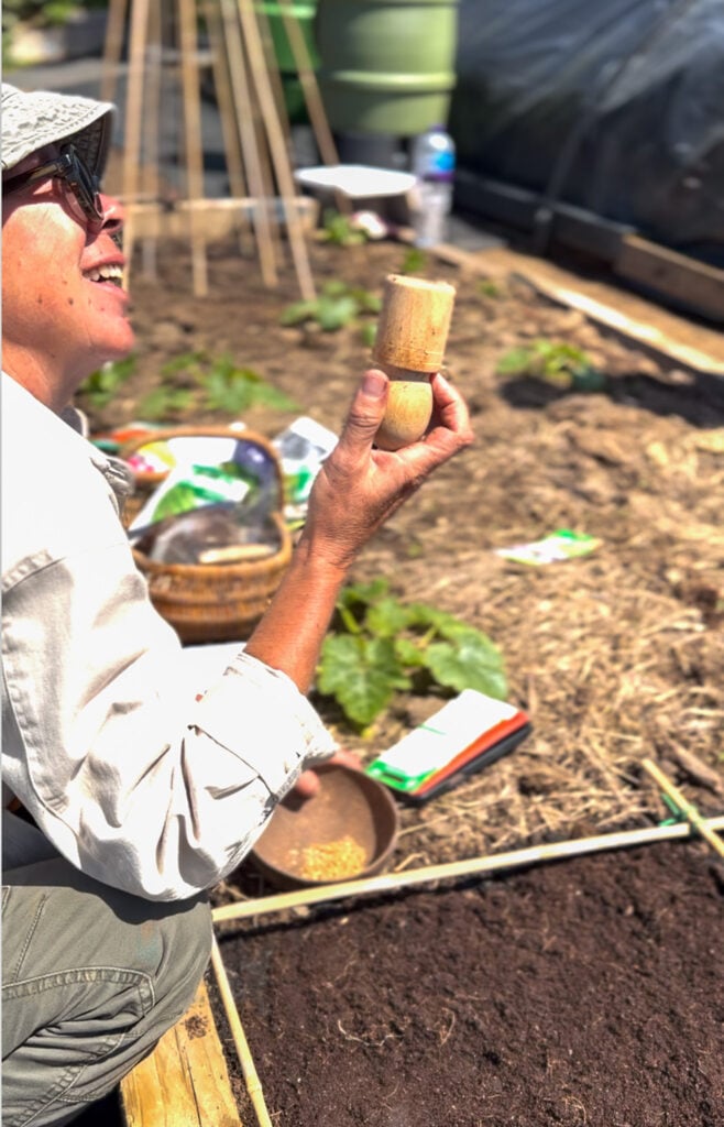 Gardener holding tool, planting seeds in soil.